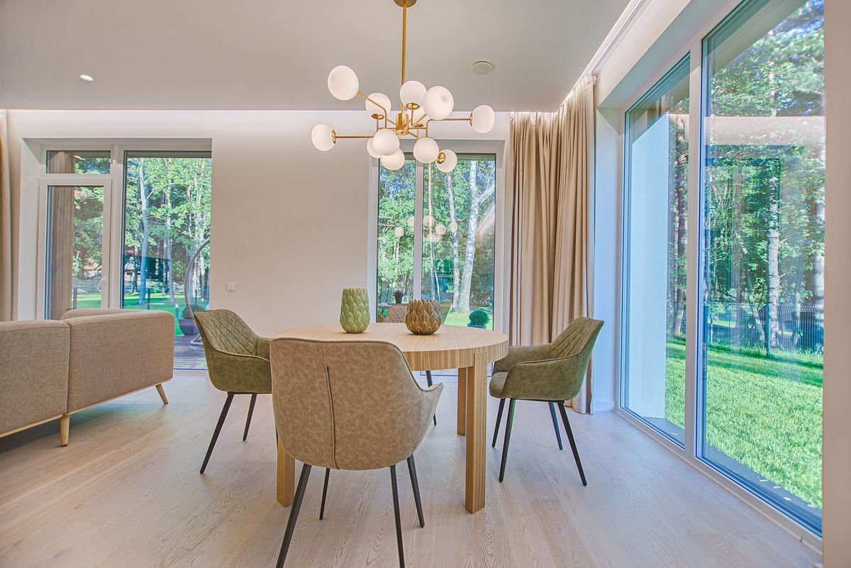 Light wide-plank flooring in a modern dining room with forest views